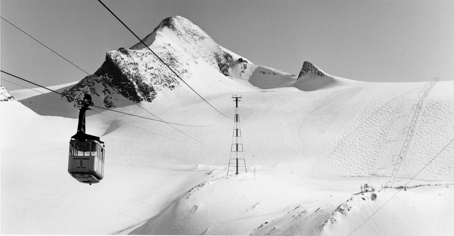Schwarze Seilbahngondel vor verschneiter Berglandschaft