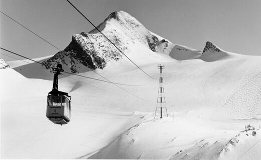 Schwarze Seilbahngondel vor verschneiter Berglandschaft