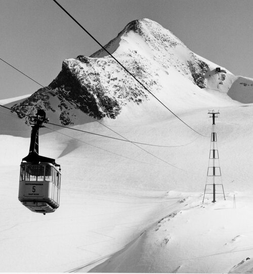 Schwarze Seilbahngondel vor verschneiter Berglandschaft