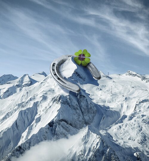 Hufeisen mit Kleeblatt auf schneebedecktem Berg vor blauem Himmel