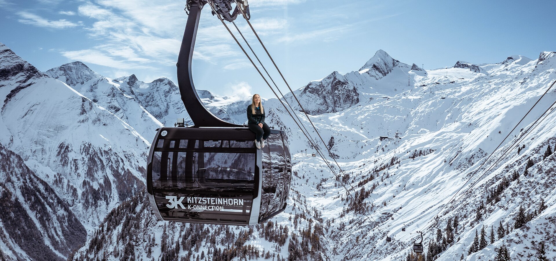 Lächelnde Frau auf Gondel vor verschneiten Bergen