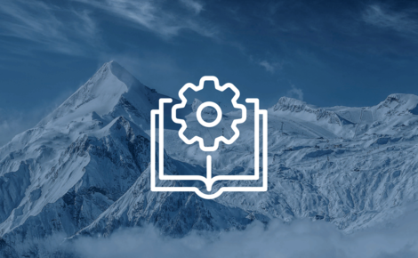 Zahnrad aufgeschlagenem Buch vor Bergkulisse