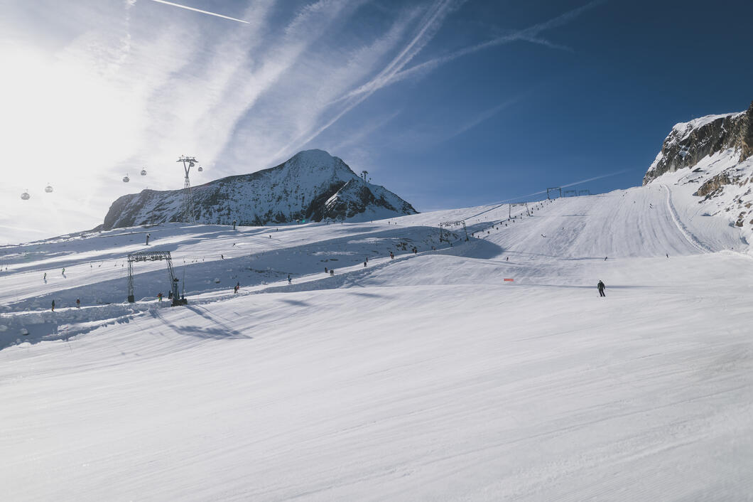 Breite verschneite Skipiste mit Skifahrern und Gondeln
