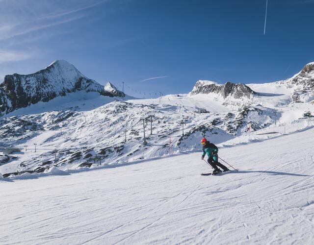 Skifahrer auf verschneiter Piste vor Bergkulisse