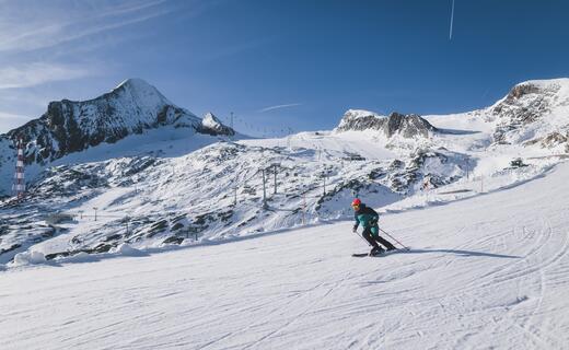Skifahrer auf verschneiter Piste vor Bergkulisse