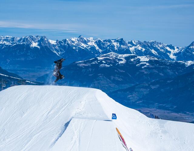 Akrobatischer Snowboarder Sprung vor alpiner Bergkulisse