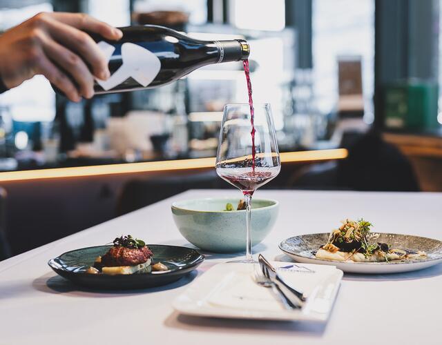 Hand pours red wine into glass on restaurant table | © Stefanie Oberhauser