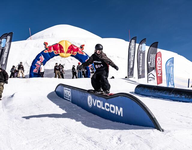 Snowboarder on a box at an event in the snow