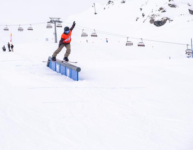 Snowboarderin Kristine Holzfeind auf Rail vor verschneiter Bergkulisse mit Liftanlagen