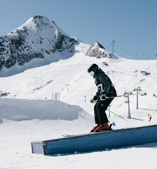 Skifahrer fährt über ein Rail im Snowpark