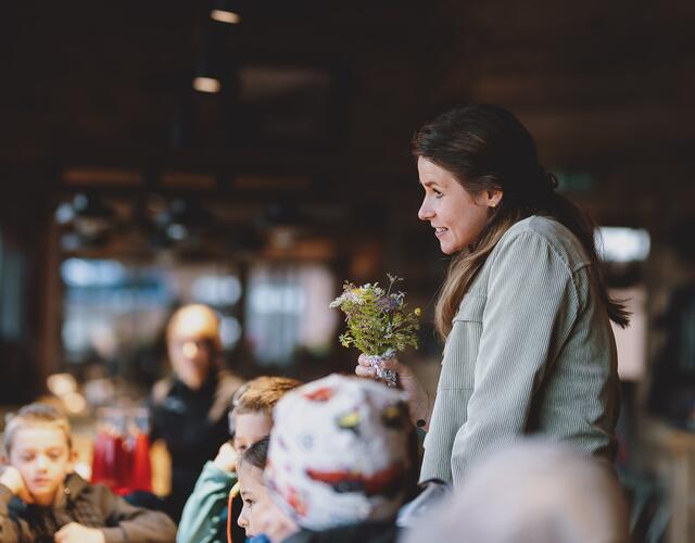 Frau mit Blumenstrauß steht vor Kindern