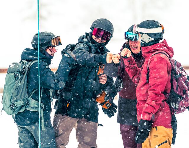 Cheerful winter sports enthusiasts fist-bumping in the snowfall