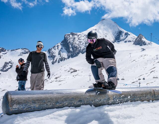 Snowboarder auf Rail vor schneebedeckter Berglandschaft