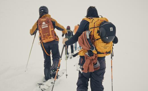 Gruppe Skitourengeher mit Rucksäcken steigt im Schnee auf
