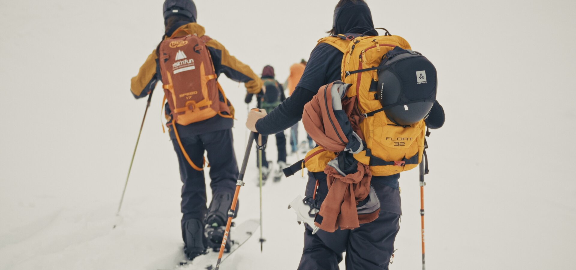Group of ski tourers with backpacks ascending in the snow