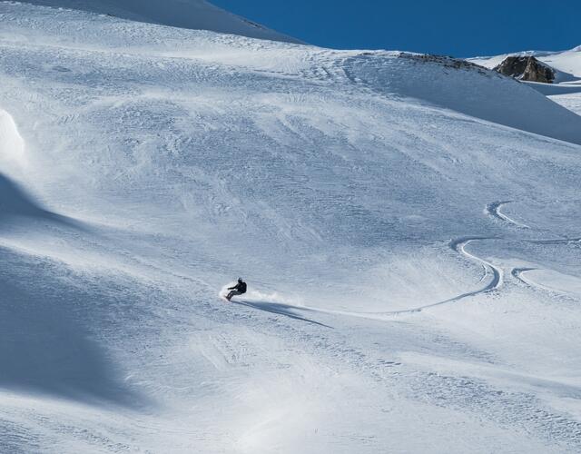 Risk'n'fun Freeride Campat the Kitzsteinhorn  | © Heli Fotoguide A snowboarder rides down a snowfield leaving beautiful tracks in the snow | © Heli Fotoguide