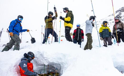 Gruppe von Skifahrern und Snowboardern untersucht eine Schneehöhle im Schnee | © Heli Düringer