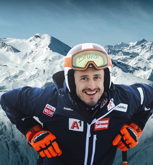 Lächelnder Skifahrer vor verschneiter Bergkulisse