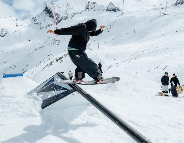 Snowboarder on rail in the snowy mountain park