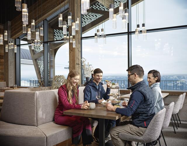 Four people are enjoying pastries with a mountain view