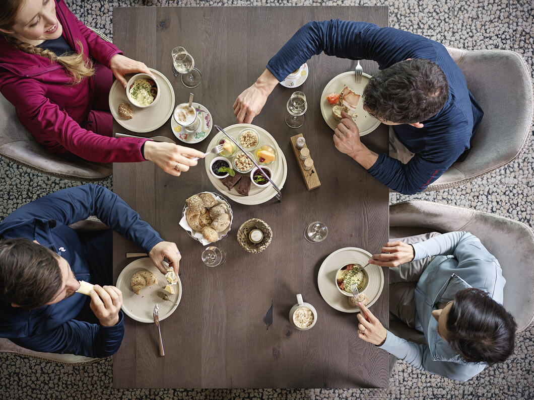 Four people having breakfast together at the wooden table