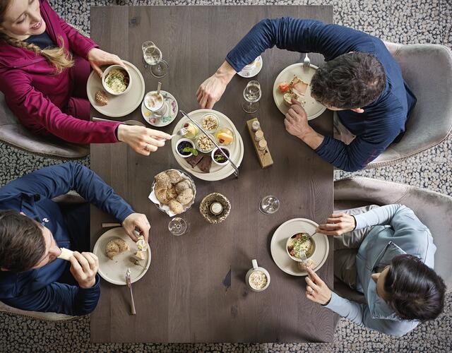 Vier Personen beim gemeinsamen Frühstück am Holztisch | © Kitzsteinhorn 