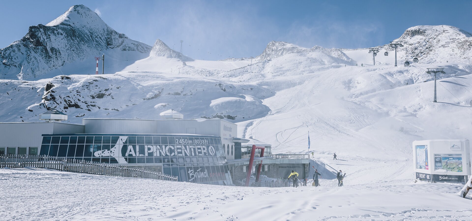Alpincenter Kitzsteinhorn im Schnee mit Bergpanorama und Skifahrern