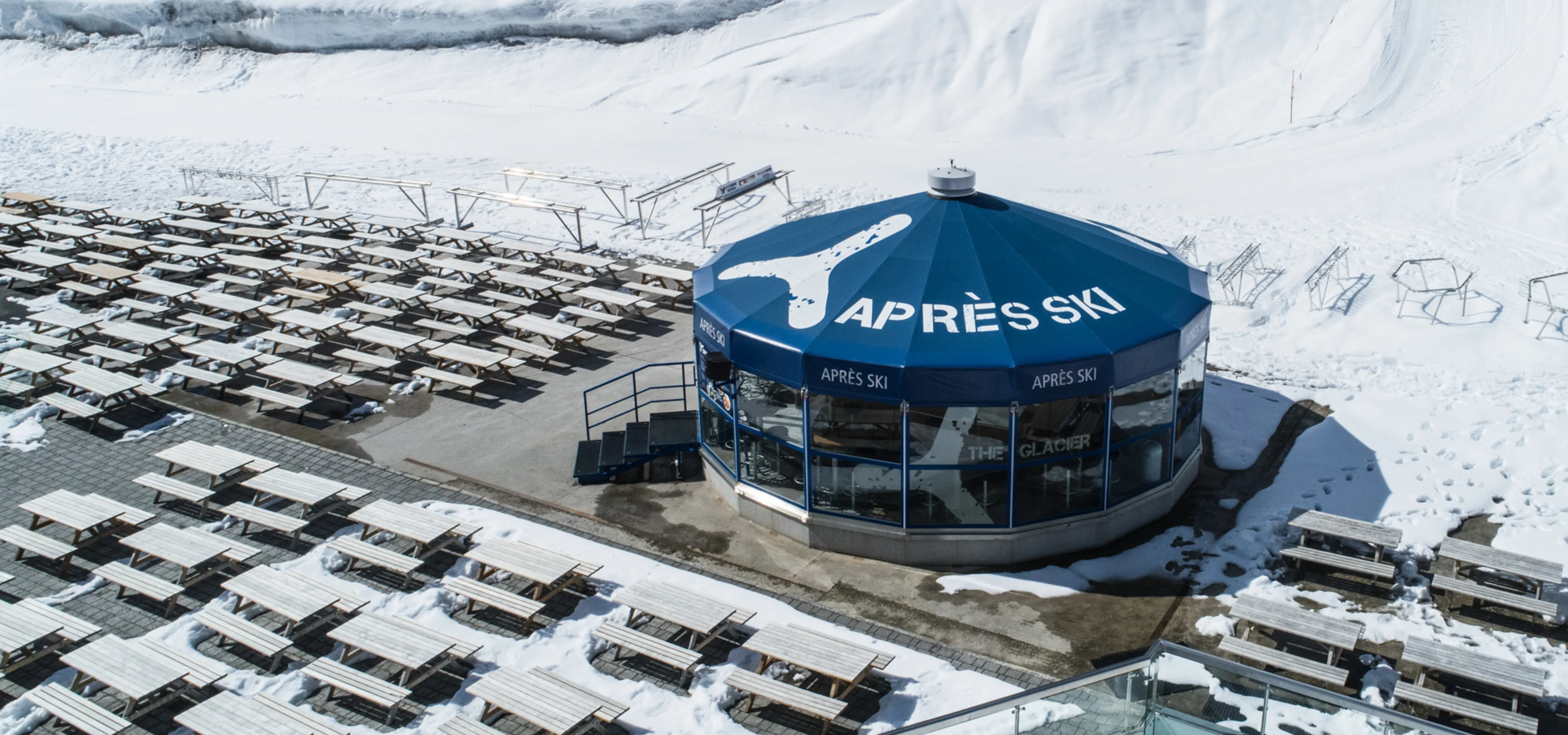 An aerial view of pet-friendly outdoor seating and exterior of Parasol Apres Sky in Kaprun, AT. Photo by Kitzsteinhorn.