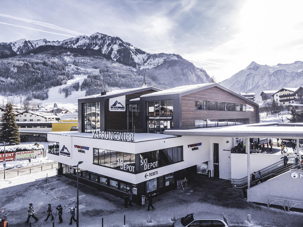 Kaprun Center | © Kitzsteinhorn Das multifunktionale Gebäude vereint Kassen, Intersport Bründl Maiskogel – einen modernen, großzügigen Sport- und Rentshop – sowie ein großzügiges Skidepot unter einem Dach. Im Depot können Gäste, die im Ort wohnen, bis zu 2.000 Skier und Schuhe deponieren und bequem zu Fuß oder mit Ski- und Dorfbus zu ihrem Hotel gelangen. | © Kitzsteinhorn
