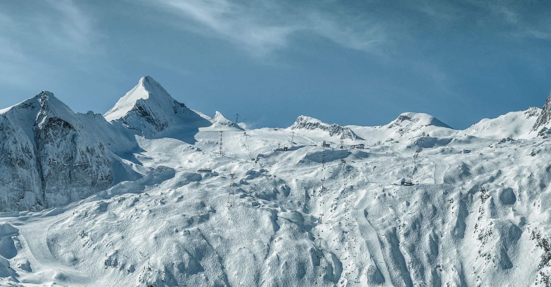 Verschneites Skigebiet Kitzsteinhorn mit Berggipfeln und Liftanlagen unter blauem Himmel