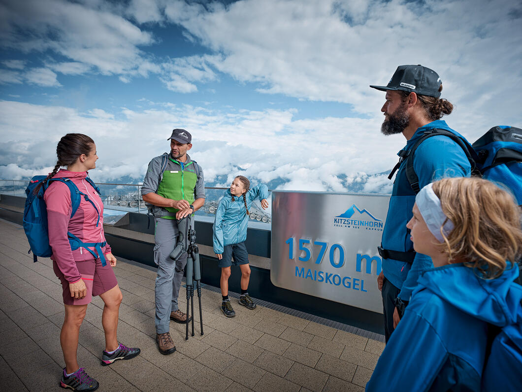 Wandergruppe steht am Aussichtspunkt Maiskogel mit Panoramablick auf die Berge