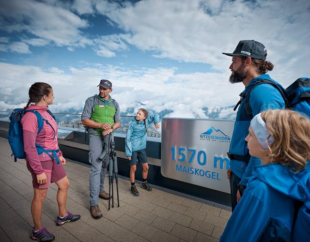Wandergruppe steht am Aussichtspunkt Maiskogel mit Panoramablick auf die Berge