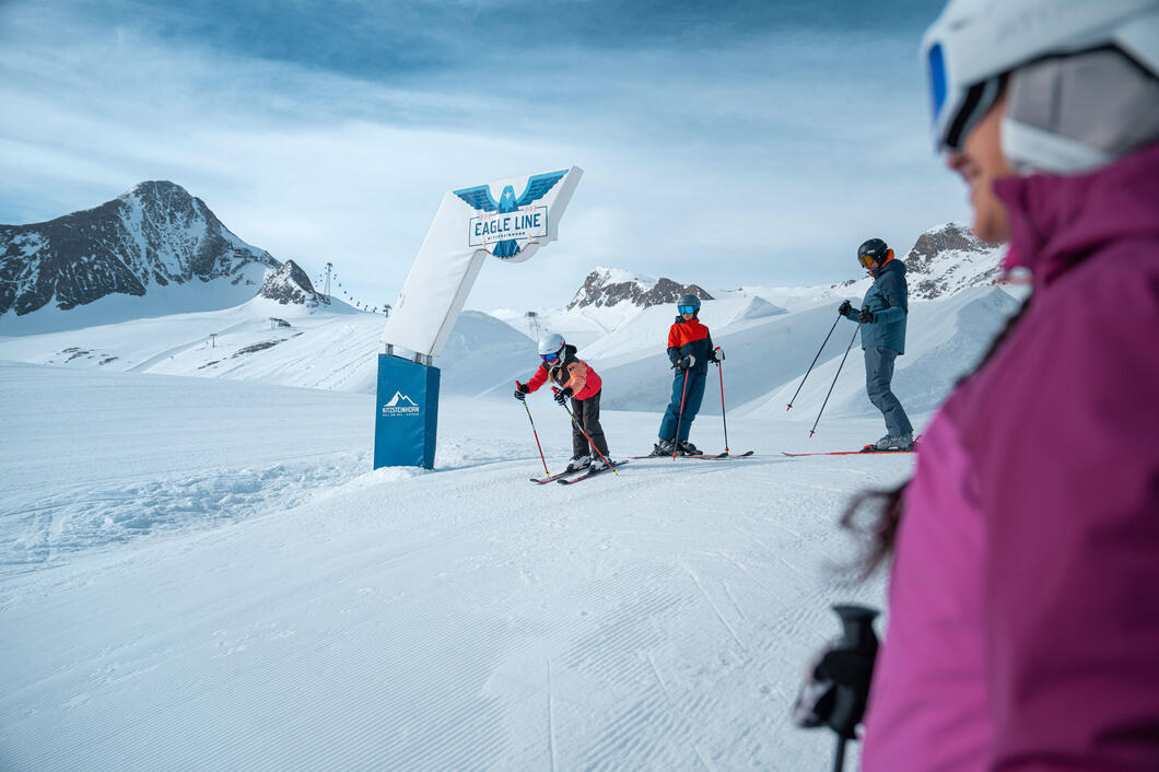 Familie fährt Ski auf dem Kitzsteinhorn an der Eagle Line bei strahlendem Sonnenschein