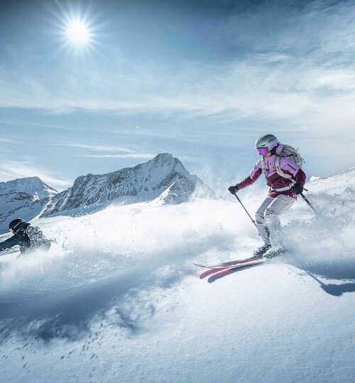 Freerider skiing in deep snow on the Kitzsteinhorn in bright sunshine