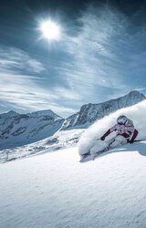 Freerider rides in deep snow on the Kitzsteinhorn, dust cloud leaves trace