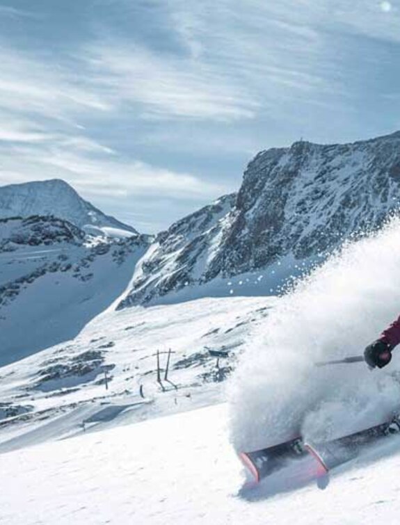 Freerider rides in deep snow on the Kitzsteinhorn, dust cloud leaves trace
