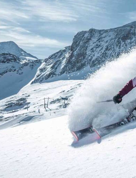 Freerider fährt im Tiefschnee am Kitzsteinhorn, Staubwolke hinterlässt Spur
