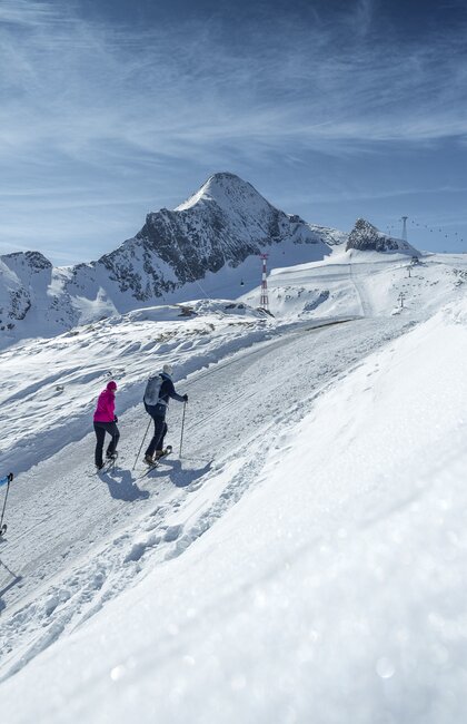 Vier Winterwanderer gehen einen Winterwanderweg am Kitzsteinhorn, umgeben von schöner Winterlandschaft | © Kitzsteinhorn 