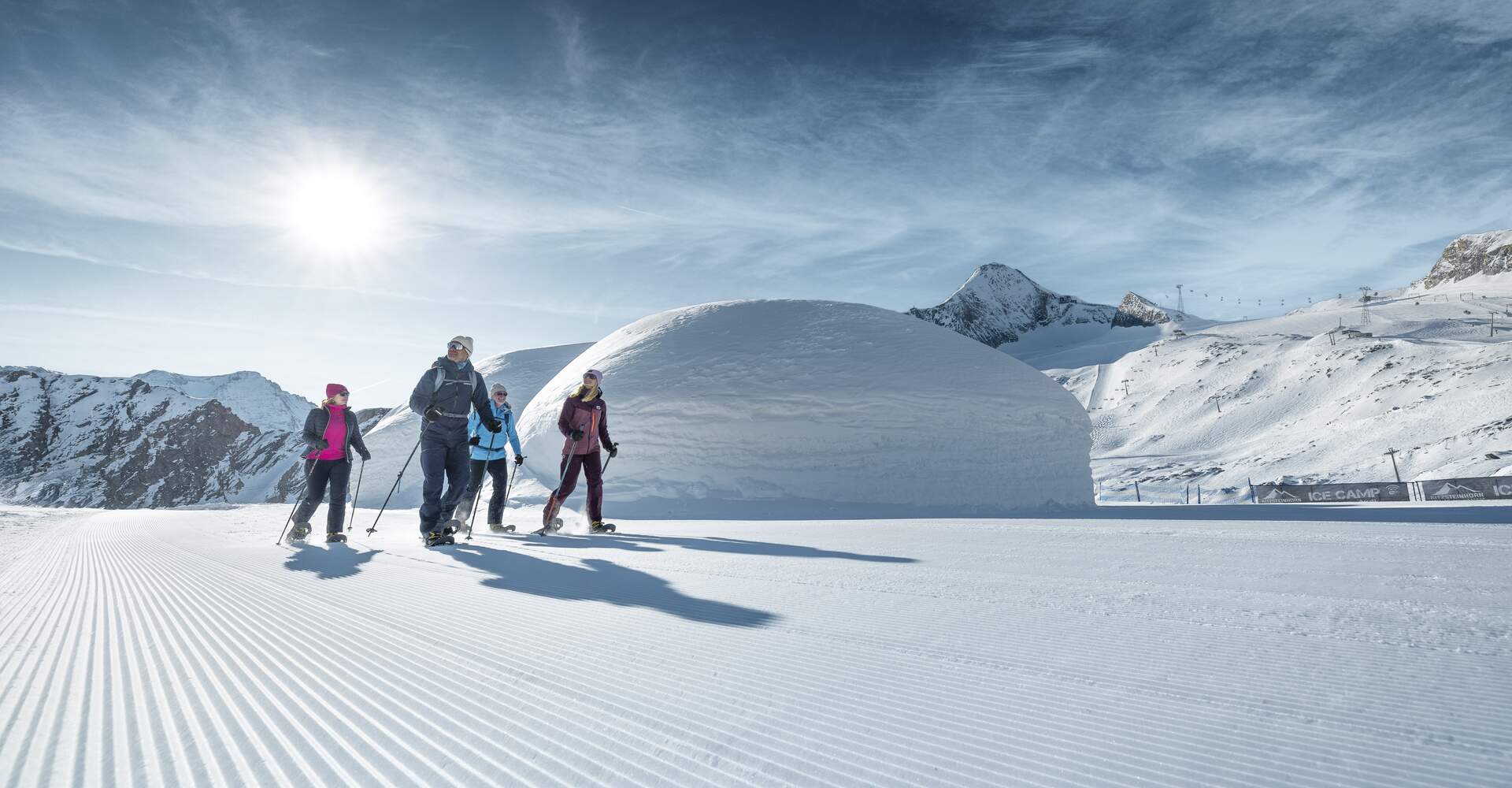 Snowshoe Hiking at Kitzsteinhorn | © Kitzsteinhorn  Four winter hikers walk a winter trail at the Kitzsteinhorn, beautiful scenery, Ice Camp igloos and the Kitzsteinhorn in the background | © Kitzsteinhorn