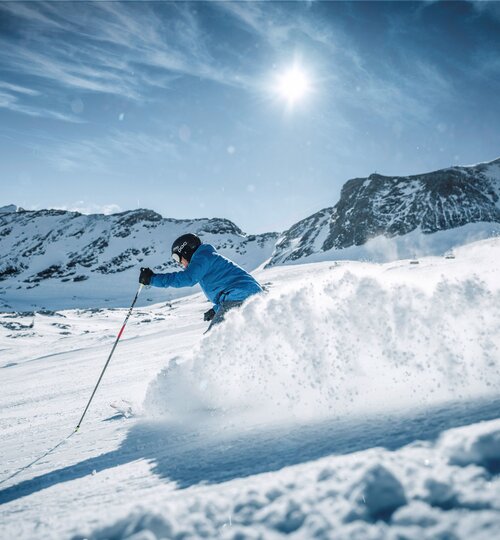 Sportlicher Skifahrer im Tiefschnee vor Bergpanorama
