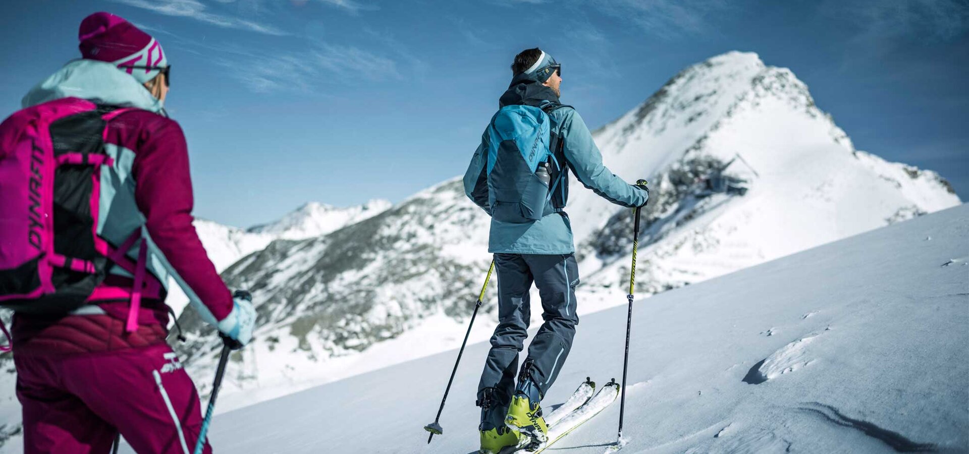 Ski tourer with backpack and skis in the snow in front of mountain panorama