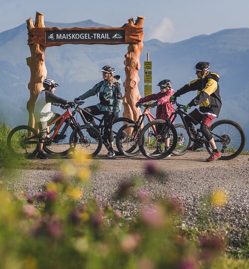 Family with mountain bikes in front of Maiskogel Trail sign in mountain landscape | © Kitzsteinhorn