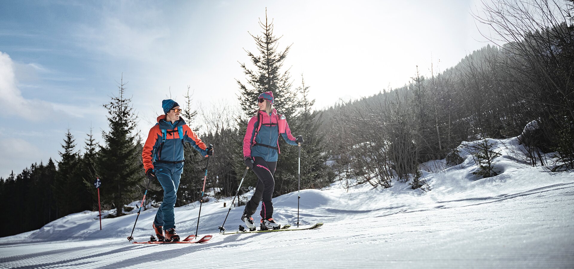 Two ski tourers on a sunny winter trail